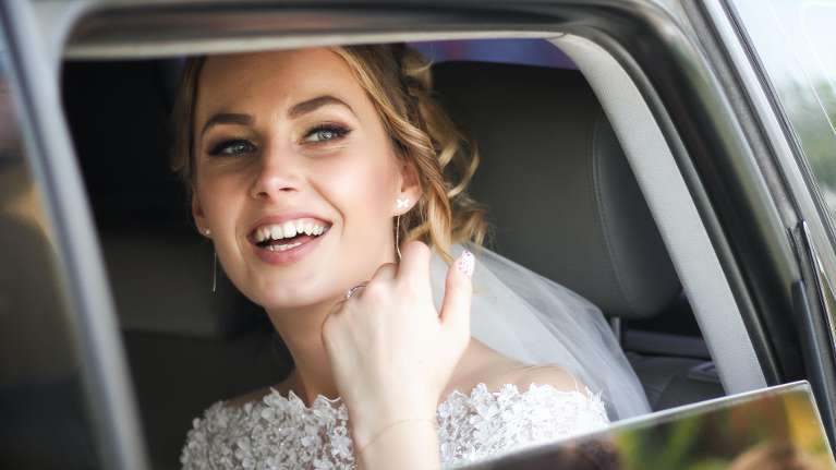 Blonde bride smiling in car, fishers in