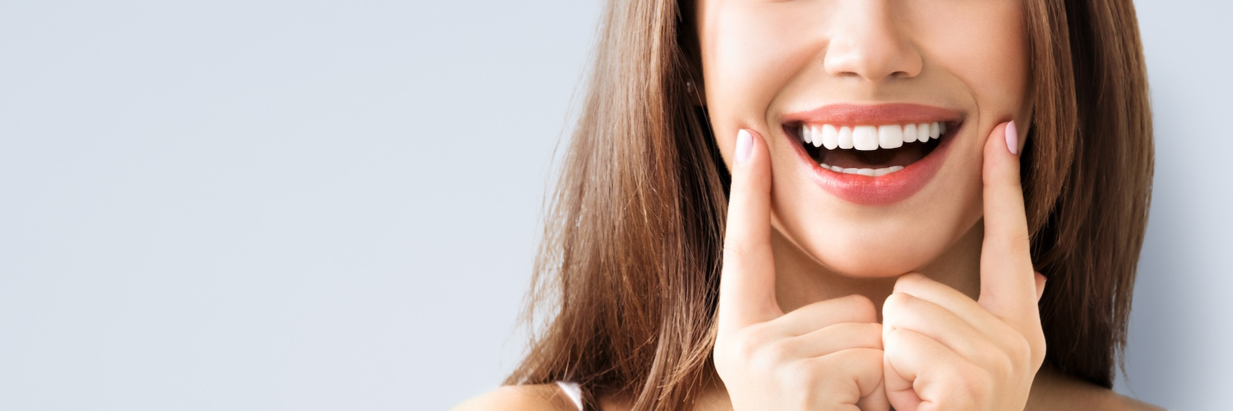 Woman pointing to her bright, white smile illustrating teeth whitening results